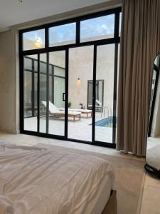 - une chambre dotée d'une grande fenêtre offrant une vue sur la piscine dans l'établissement شاليهات جزلا, à Al Hofuf