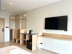 a room with a tv on a wall with a bed at The Way Hotel Ban Pong in Ban Pak Raet