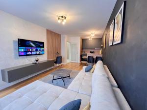 uma sala de estar com um sofá branco e uma televisão em White Homes 105 - Central Point em Podgorica