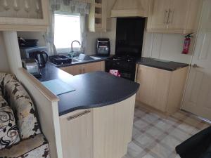 a kitchen with a black counter top and a stove at Presthaven Sands in Prestatyn