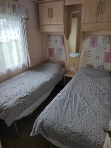 two twin beds in a bedroom with a window at Presthaven Sands in Prestatyn
