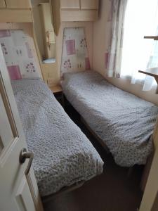 two twin beds in a small room with a window at Presthaven Sands in Prestatyn
