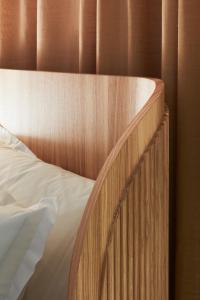 a bed with a wooden headboard and white sheets at Zzz Dreamscape Hotel in Stockholm
