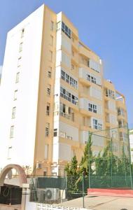een hoog gebouw met een hek ervoor bij Apartamento Bitacora in Playa de Gandia