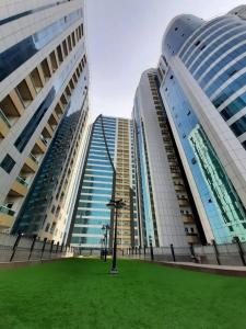 two tall buildings with a grass field between them at Panorama Sea view Studio in Ajman 