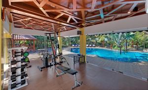 a gym with a swimming pool and exercise equipment at The Fern Gir Forest Resort, Sasan Gir - A Fern Crown Collection Resort in Sasan Gir