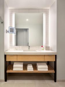uma casa de banho com um lavatório e um espelho grande em The Viv Hotel, Anaheim, a Tribute Portfolio Hotel em Anaheim