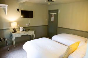 a hotel room with two beds and a desk and a tv at Ye Old Boote Inn in Whittington