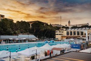 a large swimming pool with white umbrellas and buildings at Arena Albaro House in Genoa