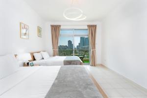 a bedroom with two beds and a large window at Lux BnB I Una Tower I Lakes View in Dubai