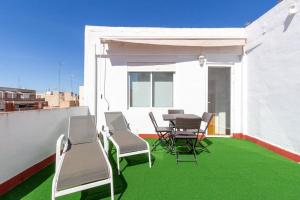 eine Terrasse mit Stühlen, einem Tisch und grünem Gras in der Unterkunft Apartamento Ático Duplex Santa Pola in Santa Pola
