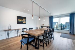 a dining room with a wooden table and chairs at Flat White - Luxe app aan zee met terras & parking in De Haan +22 photos