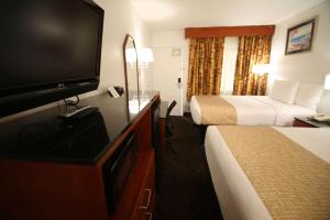 a hotel room with two beds and a flat screen tv at Travelodge by Wyndham Burbank-Glendale in Burbank
