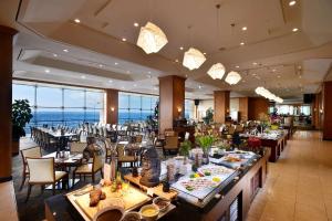 a restaurant with tables and chairs and a view of the ocean at Ramada Plaza by Wyndham Jeju Ocean Front in Jeju