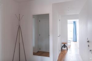 a white room with a mirror and a tripod at Flat White - Luxe app aan zee met terras & parking in De Haan