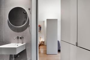 ein Bad mit einem Waschbecken und einem Wandspiegel in der Unterkunft Paddington Studio By Morethanstays in London