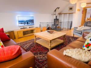 a living room with couches and a table and a tv at Dalfern Lodge in Aviemore