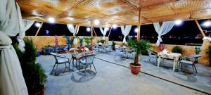 ein Restaurant mit Tischen und Stühlen unter einem Dach in der Unterkunft Naqshband in Buxoro