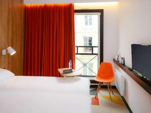 カーンにあるibis Styles Caen Centre Historiqueのベッドとオレンジの椅子が備わるホテルルームです。