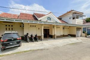 un coche aparcado frente a una casa con tres motocicletas en Urbanview Hotel Sany Cirebon en Tangkil