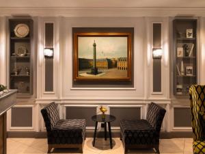 a room with two chairs and a table and a painting at Hotel Stendhal Place Vendôme Paris - MGallery in Paris