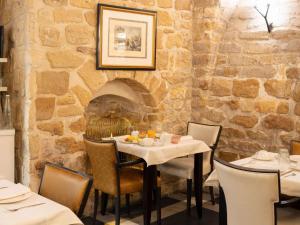 uma sala de jantar com mesas e cadeiras e uma parede de pedra em Hotel Stendhal Place Vendôme Paris - MGallery em Paris