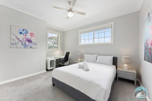 a white bedroom with a bed and a desk at Aircabin - Blakehurst - Spacious - 5 Beds House in Sydney