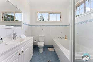 a white bathroom with a tub and a toilet and a sink at Aircabin - Blakehurst - Spacious - 5 Beds House in Sydney +19 photos