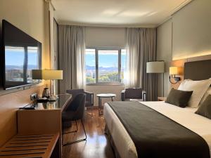 um quarto de hotel com uma cama, uma secretária e cadeiras em Barceló Murcia Siete Coronas em Múrcia