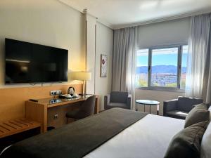 a hotel room with a bed and a flat screen tv at Barceló Murcia Siete Coronas in Murcia
