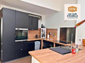 eine Küche mit schwarzen Schränken und einer hölzernen Arbeitsplatte in der Unterkunft Appartement climatisé avec sa terrasse de 25 M2 in Limoges