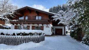 uma casa de madeira com uma cerca na neve em Haus Elisabeth Schwaiger em Maria Alm am Steinernen Meer