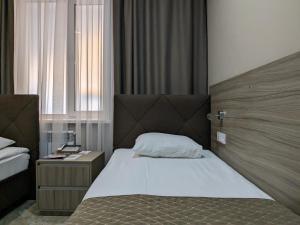 1 dormitorio con 1 cama con cabecero de madera en Victoria Hotel, en Uralsk