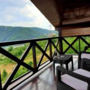d'un balcon avec une table et une vue sur les montagnes. dans l'établissement Pensiunea Decebal Resort - Cazanele Dunarii, à Dubova