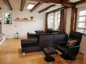 ein Wohnzimmer mit einem schwarzen Sofa und Stühlen in der Unterkunft Ferienwohnung Wennetal in Schmallenberg