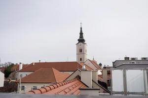 een kerktoren met een klokkentoren op daken bij Apartman “Manhattan” in Križevci