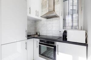 a white kitchen with white cabinets and a sink at GuestReady - Sunlit Serenity near Montmartre in Paris