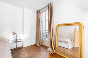 a mirror in a bedroom with a bed and a window at GuestReady - Sunlit Serenity near Montmartre in Paris