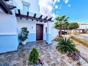 una casa blanca con una puerta marrón y algunas plantas en Palmito Luxury La Torre Golf Resort Murcia, en Roldán