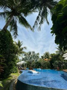 einen Pool in einem Resort mit Palmen in der Unterkunft Villa Đà Nẵng Gần Biển - Biệt Thự Đà Nẵng in Đà Nẵng