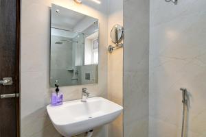 a white bathroom with a sink and a mirror at AVS Prime in kolkata