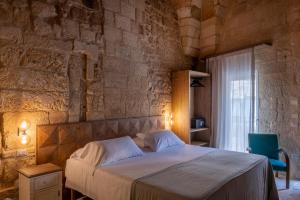 a bedroom with a bed and a stone wall at Palazzo Sant'Anna Lecce in Lecce