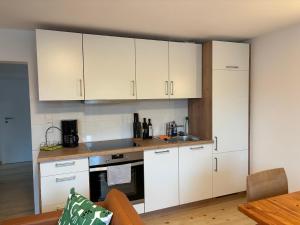 a kitchen with white cabinets and a stove top oven at Wick Home Apartment 1 in Burgheim