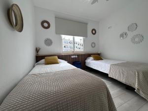 twee bedden in een kamer met witte muren en een raam bij Apartamento en Cala en Porter, Menorca. in Cala'n Porter