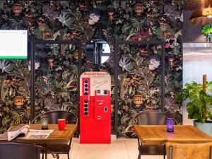 una máquina de coca roja en una habitación con mesas en ibis Styles Puteaux Paris La Defense en Puteaux