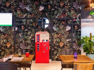 a red coke machine in a room with tables at ibis Styles Puteaux Paris La Defense in Puteaux