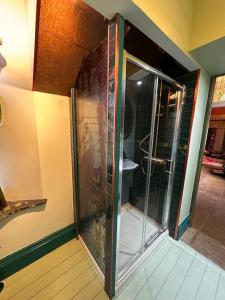 a glass shower door in a room with a bathroom at Victorian Copper Cottage in Lancaster