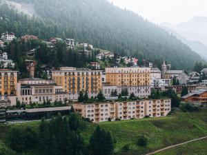 a group of buildings on a hill with a mountain at Kulm Hotel St. Moritz in St. Moritz
