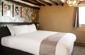 um quarto com uma grande cama branca num quarto em Narborough Arms em Narborough