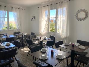 una sala da pranzo con tavoli, sedie e finestre di L'Isula Rossa a LʼÎle-Rousse